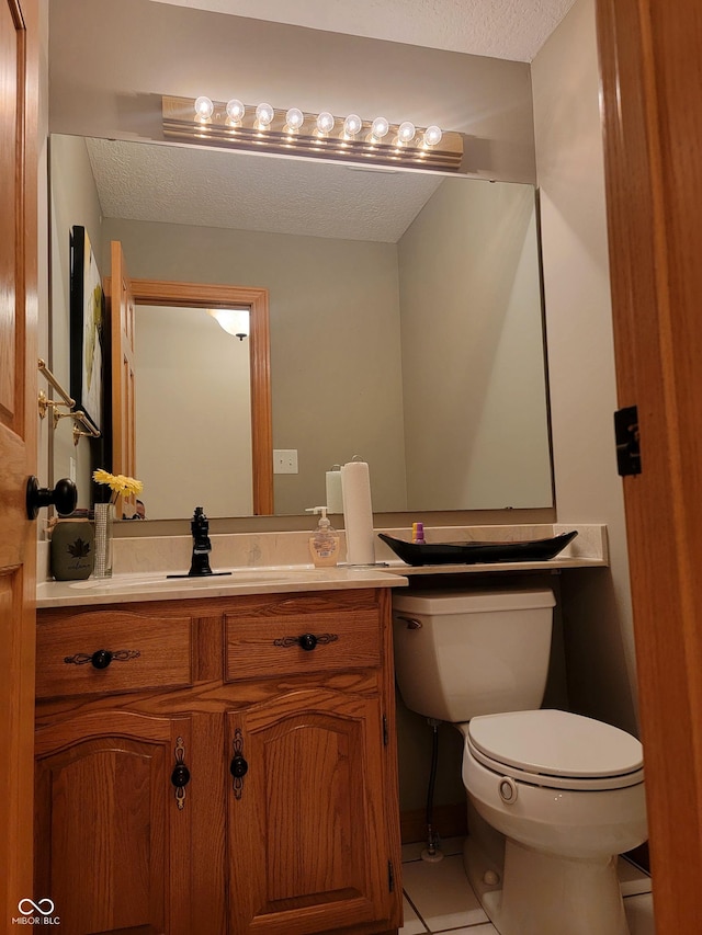 bathroom with toilet, a textured ceiling, vanity, and tile patterned floors