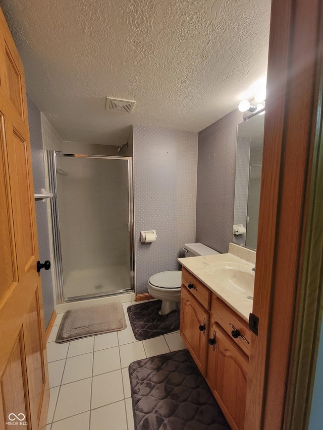 bathroom featuring tile patterned floors, a shower with door, vanity, and toilet