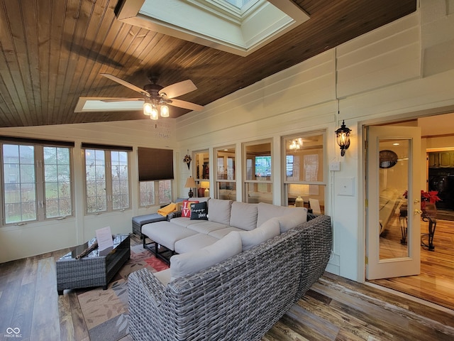 living room featuring wood ceiling, lofted ceiling with skylight, ceiling fan, hardwood / wood-style floors, and wood walls