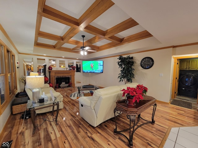 living room with ceiling fan, coffered ceiling, light hardwood / wood-style flooring, beamed ceiling, and washer / dryer