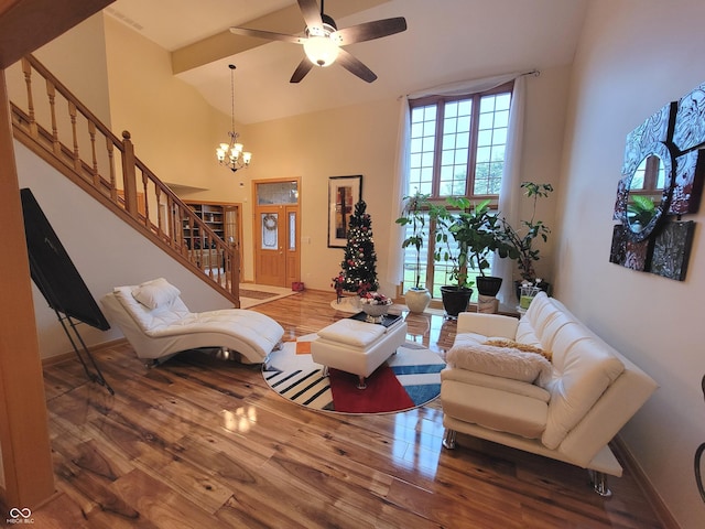 living room featuring hardwood / wood-style floors, ceiling fan with notable chandelier, and a towering ceiling