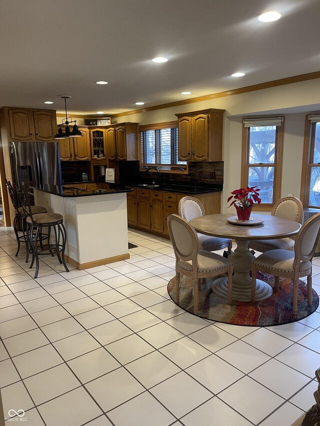 kitchen with decorative backsplash, ornamental molding, stainless steel fridge with ice dispenser, a center island, and light tile patterned flooring