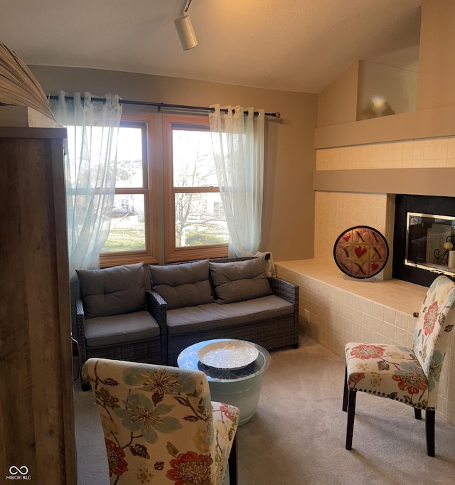 carpeted living room featuring a fireplace, rail lighting, and vaulted ceiling