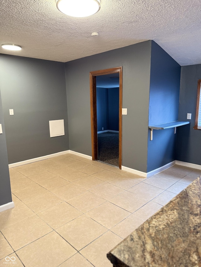 unfurnished room with light tile patterned floors and a textured ceiling