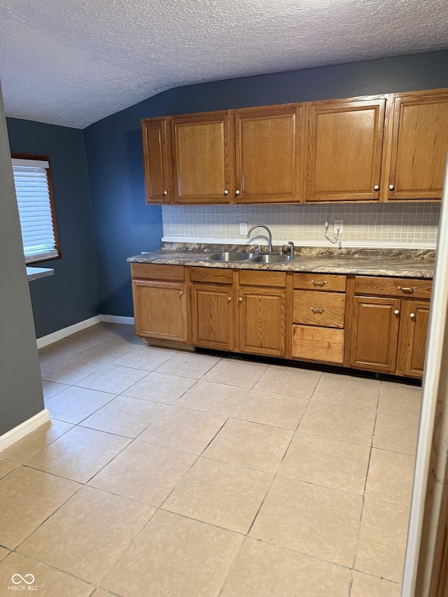 kitchen with light tile patterned flooring, a textured ceiling, and sink