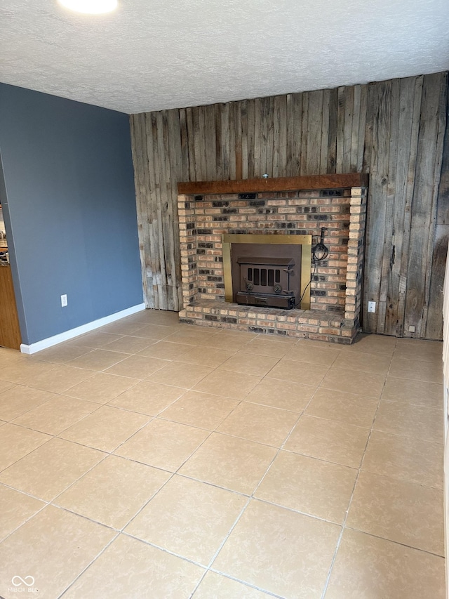 unfurnished living room featuring a textured ceiling, a brick fireplace, and wood walls