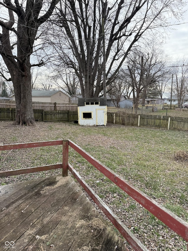 wooden terrace featuring a yard and a storage unit