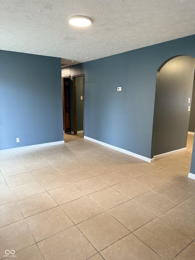 unfurnished room featuring light tile patterned floors and a textured ceiling