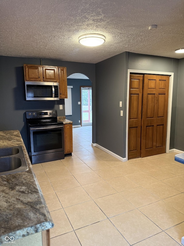 kitchen featuring a textured ceiling, light tile patterned flooring, sink, and stainless steel appliances