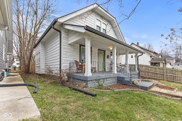 bungalow featuring covered porch and a front yard