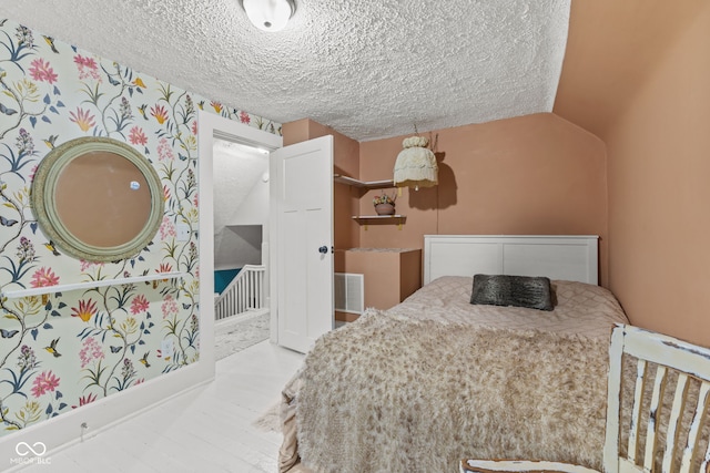 bedroom with a textured ceiling and vaulted ceiling