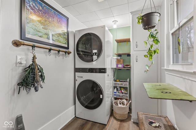 laundry area featuring dark hardwood / wood-style floors and stacked washer / drying machine