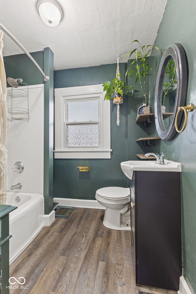 full bathroom with tub / shower combination, vanity, a textured ceiling, wood-type flooring, and toilet