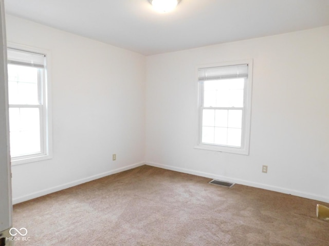 unfurnished room featuring plenty of natural light and light carpet