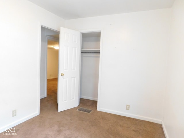 unfurnished bedroom with a closet and light carpet