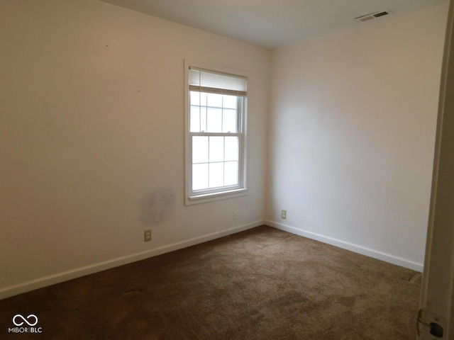 spare room featuring dark colored carpet