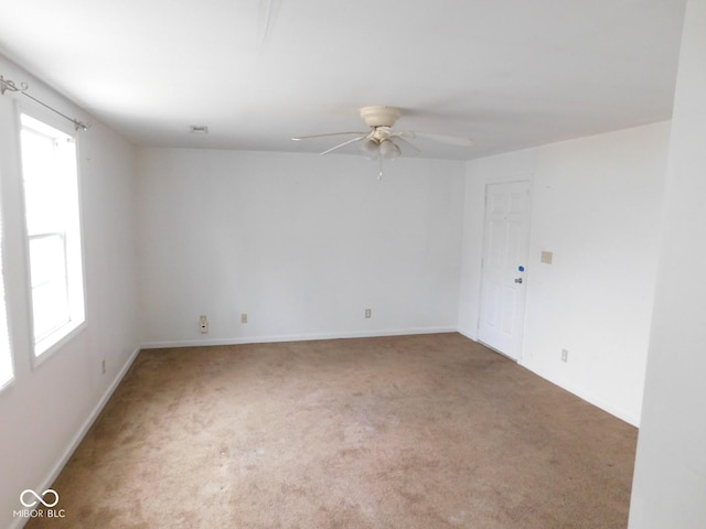 carpeted spare room with ceiling fan and plenty of natural light