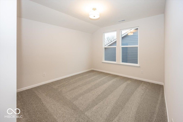 spare room featuring carpet and lofted ceiling