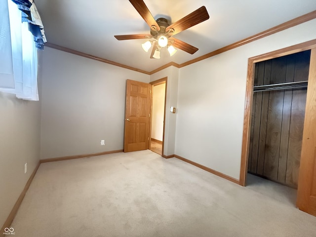 unfurnished bedroom with crown molding, a closet, light carpet, ceiling fan, and baseboards