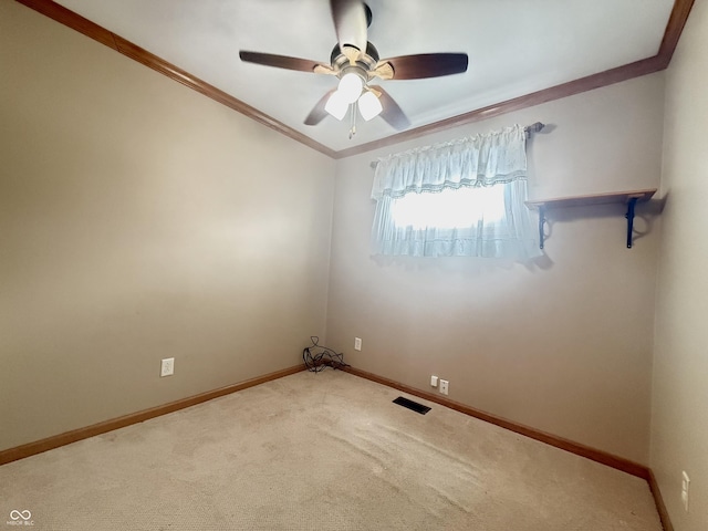 carpeted spare room with baseboards, visible vents, ornamental molding, and ceiling fan