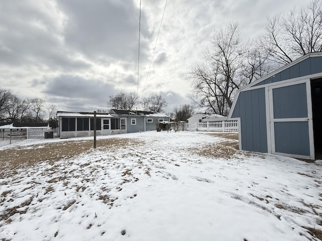 yard layered in snow featuring a storage shed, fence, and an outbuilding