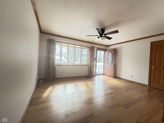 empty room with ornamental molding, ceiling fan, light wood finished floors, and baseboards