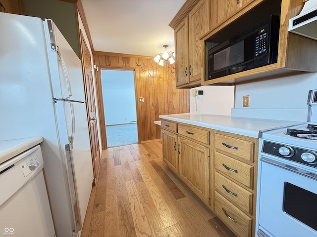 kitchen with white appliances, light wood-style flooring, light countertops, wood walls, and under cabinet range hood