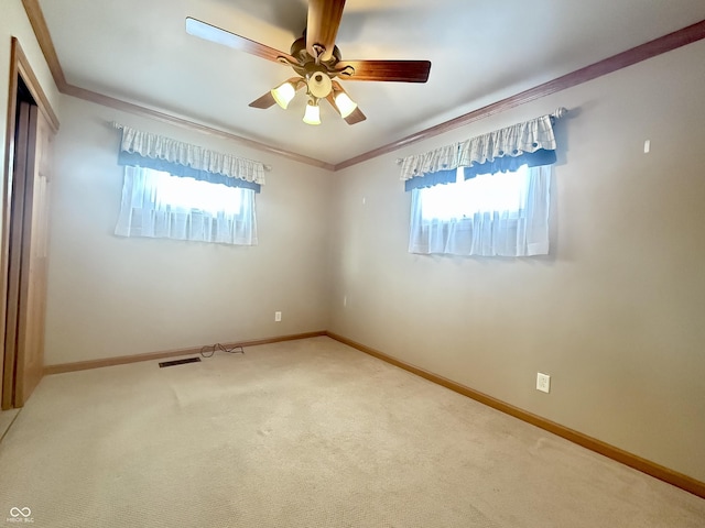 carpeted empty room with ornamental molding, a wealth of natural light, and baseboards