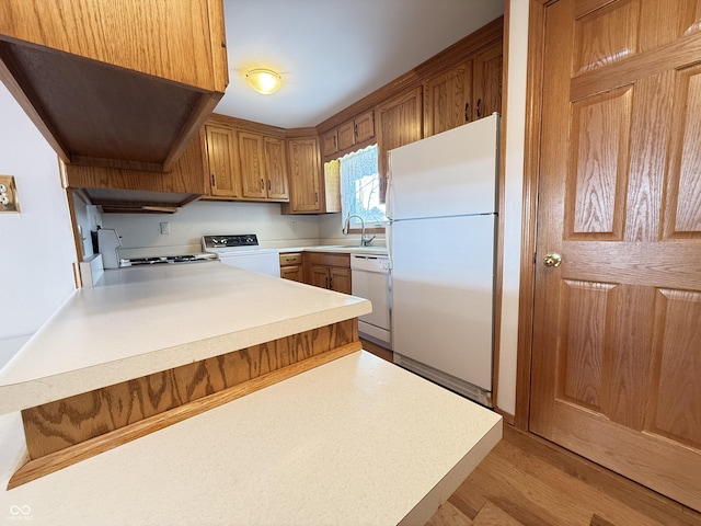 kitchen featuring light wood-style floors, white appliances, light countertops, and a peninsula