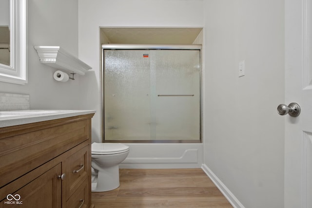 full bathroom with hardwood / wood-style floors, vanity, toilet, and bath / shower combo with glass door