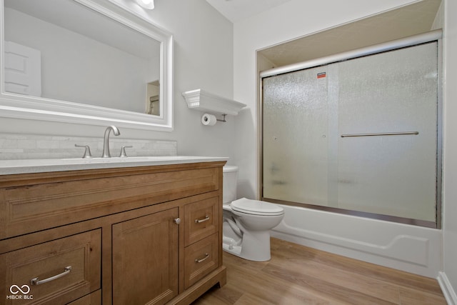 full bathroom with toilet, vanity, hardwood / wood-style floors, and combined bath / shower with glass door