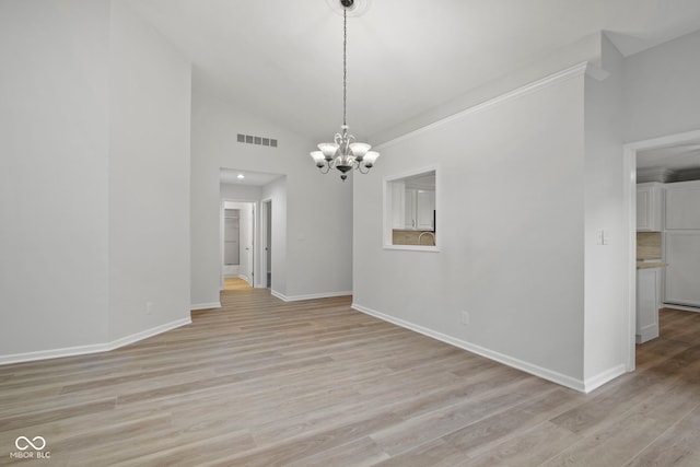 unfurnished room with a notable chandelier, light wood-type flooring, and lofted ceiling