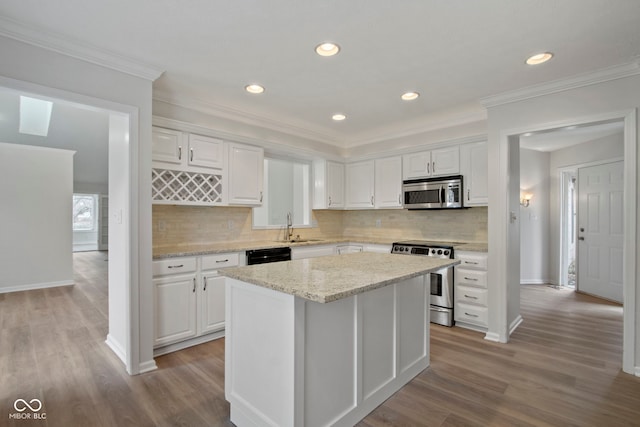 kitchen featuring white cabinetry, sink, decorative backsplash, a kitchen island, and appliances with stainless steel finishes