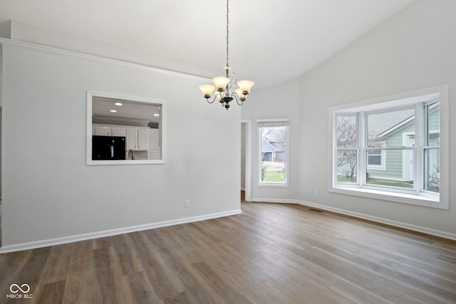 unfurnished room featuring wood-type flooring, vaulted ceiling, and a notable chandelier