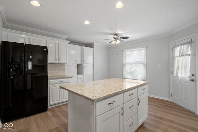 kitchen featuring a center island, white cabinets, black fridge, light wood-type flooring, and tasteful backsplash