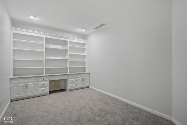 unfurnished office featuring built in desk and light carpet