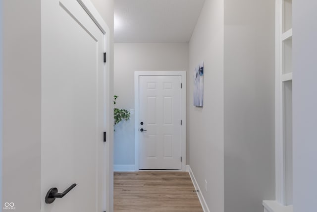 hallway with a textured ceiling and light hardwood / wood-style flooring