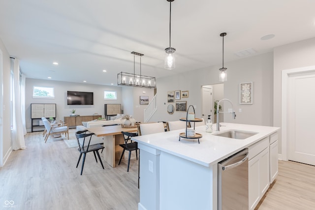 kitchen with dishwasher, sink, hanging light fixtures, an island with sink, and white cabinetry