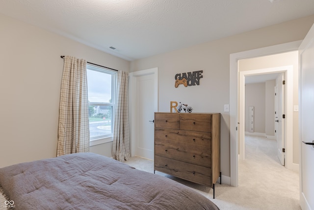 bedroom featuring a textured ceiling and light colored carpet