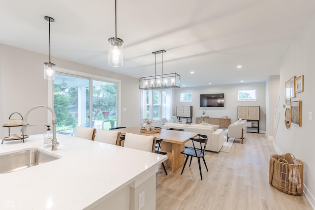 kitchen with light hardwood / wood-style floors, hanging light fixtures, and sink