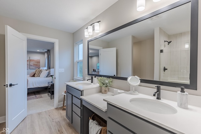 bathroom with hardwood / wood-style floors, vanity, and tiled shower