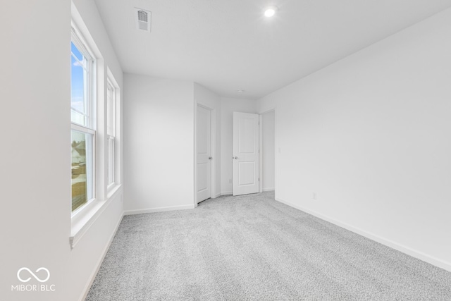 unfurnished room featuring light carpet, visible vents, and baseboards