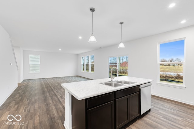 kitchen with a kitchen island with sink, a sink, open floor plan, stainless steel dishwasher, and pendant lighting