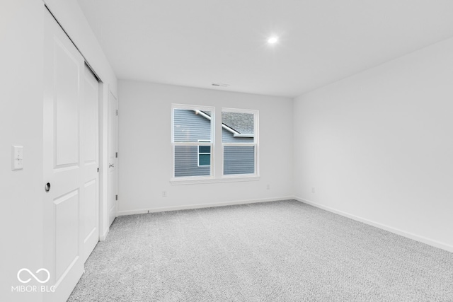 unfurnished bedroom with visible vents, baseboards, a closet, and light colored carpet