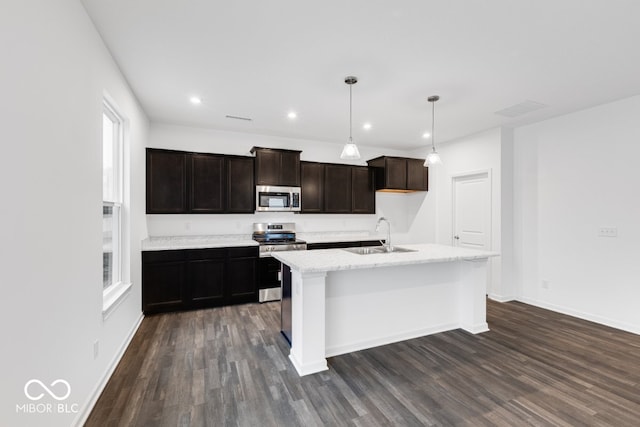 kitchen featuring a sink, appliances with stainless steel finishes, dark wood-style floors, an island with sink, and pendant lighting