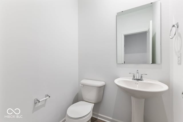 bathroom with a sink, toilet, and baseboards