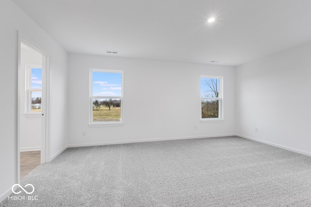 unfurnished room featuring light colored carpet, visible vents, and baseboards