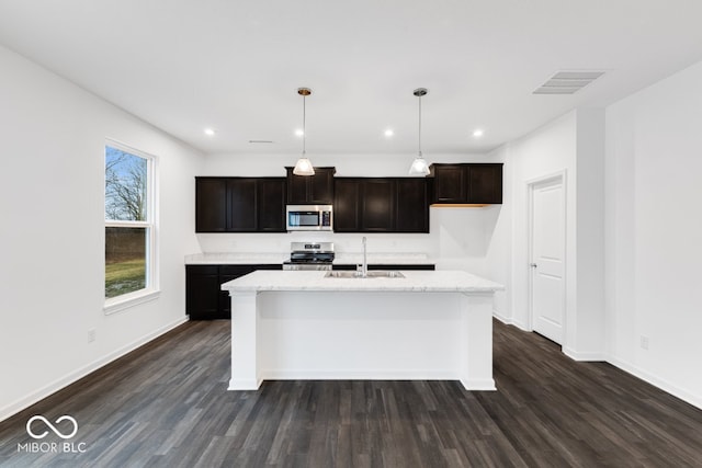 kitchen with stainless steel appliances, visible vents, hanging light fixtures, a kitchen island with sink, and a sink