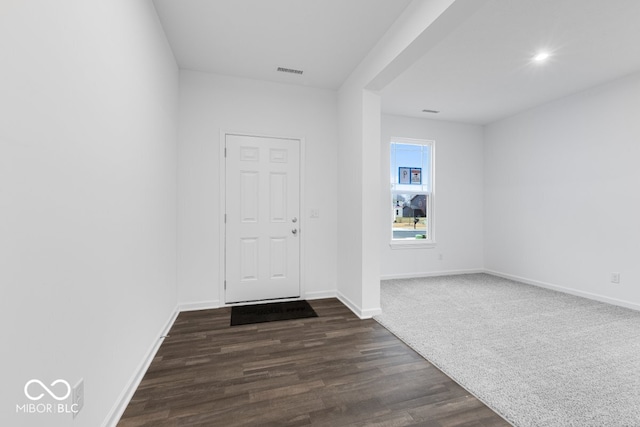 foyer entrance with dark wood-type flooring, visible vents, and baseboards