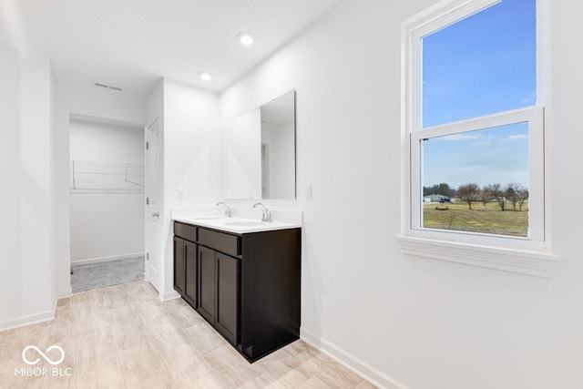 full bathroom featuring double vanity, visible vents, a spacious closet, and baseboards